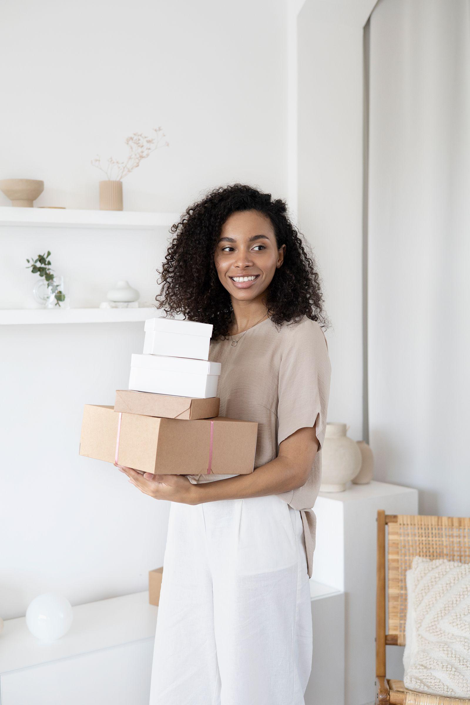 An online shop owner smiling as she carries a stack of parcels